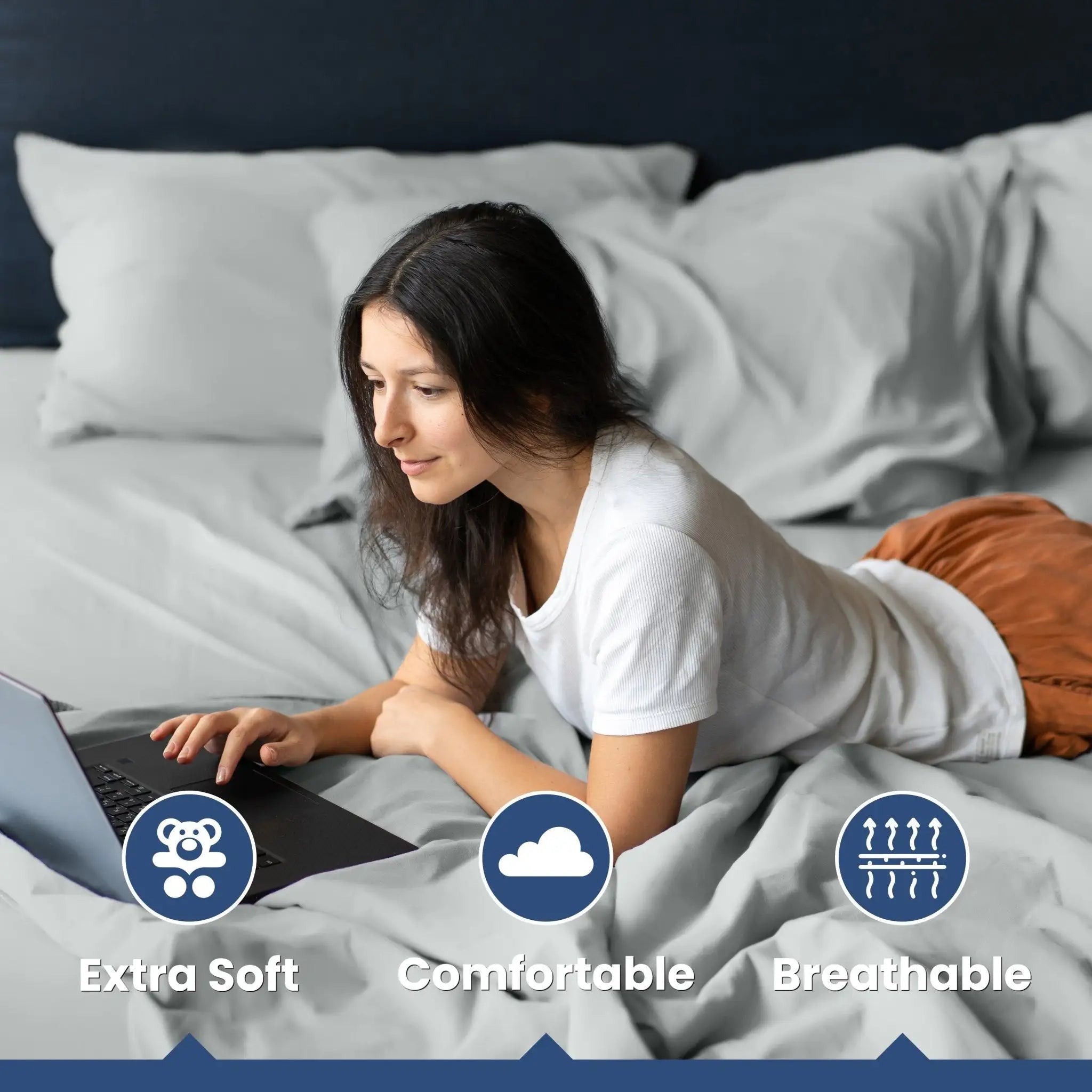 Woman using a laptop on a bed with text labels 'Extra Soft', 'Comfortable', and 'Breathable'.