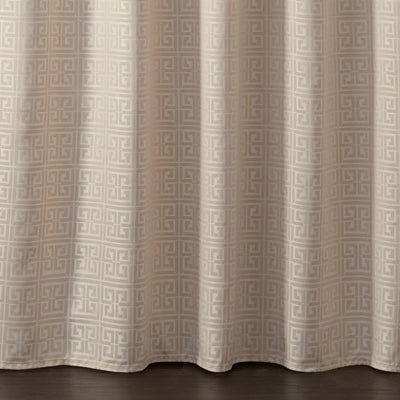 Beige curtain panel with a repeating geometric Greek key pattern in a light taupe, hanging over a dark wood floor.