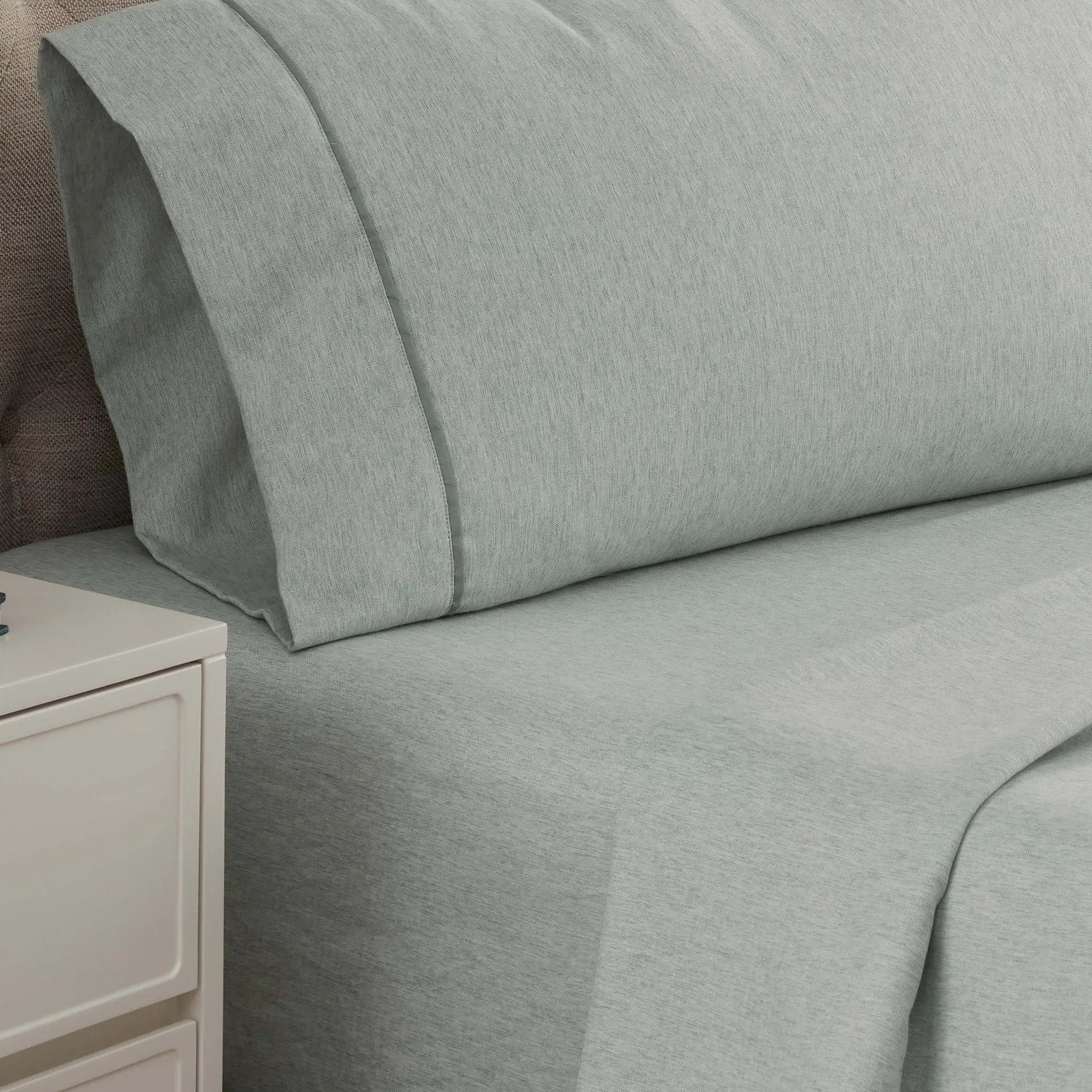 Gray bed sheets and pillowcase set on a bed with a nightstand.