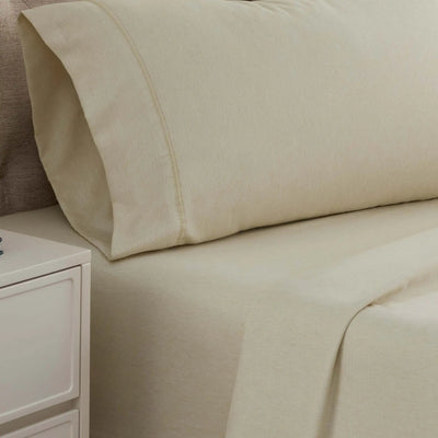 Beige bed sheets and pillow on a bed with a nightstand in the corner.