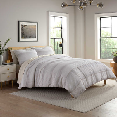 Neatly made bed with striped comforter set in a bright bedroom