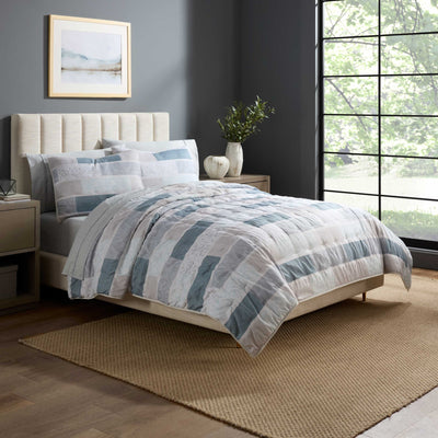 Bedroom with a neatly made bed featuring a plaid quilt set.
