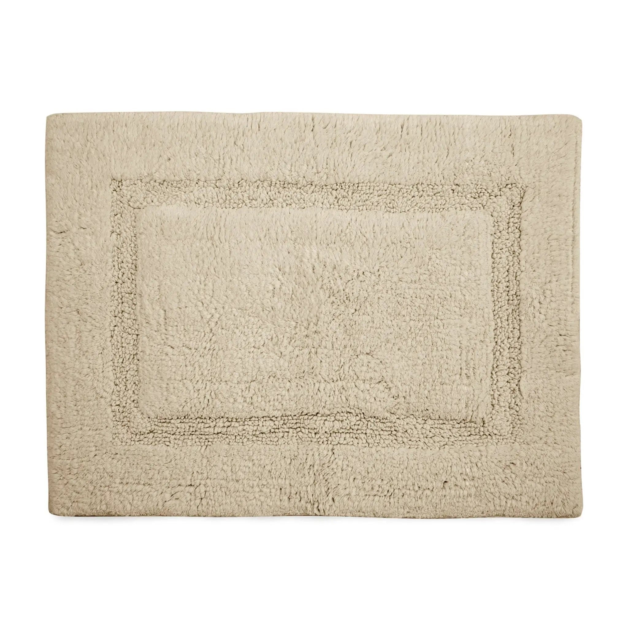 A rectangular cream bath rug with a raised border design, shown flat against a solid white background.