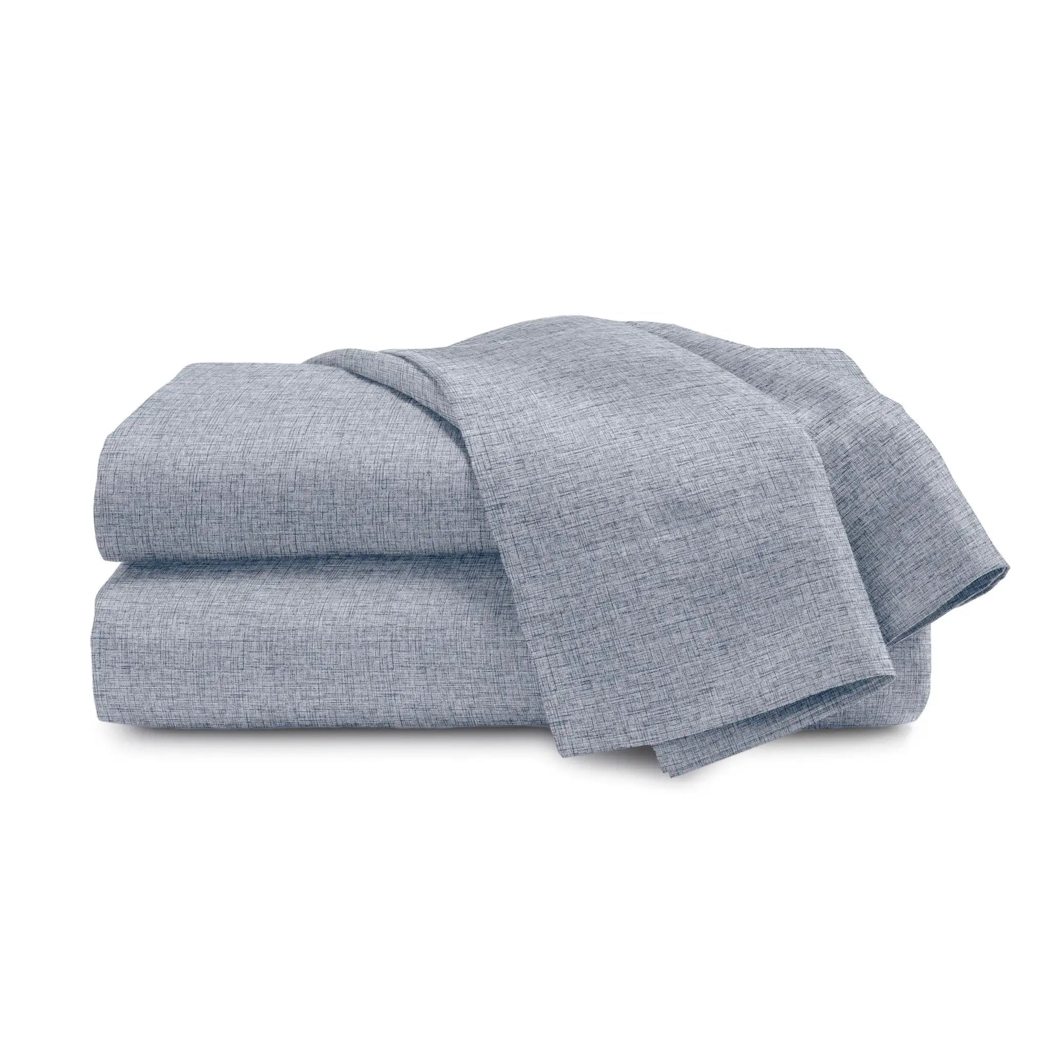 A folded stack of light blue-gray textured fabric sheets or blankets on a plain white background.