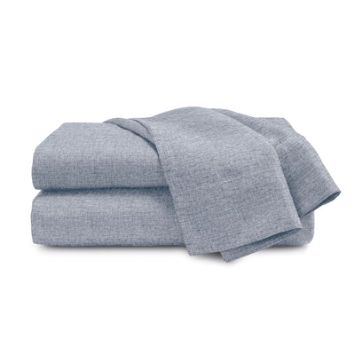 A folded stack of light blue-gray textured fabric sheets or blankets on a plain white background.