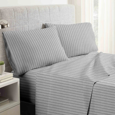 Gray striped bed sheets on a neatly made bed with pillows.