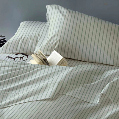 Striped bedding with glasses and an open book on a bed.