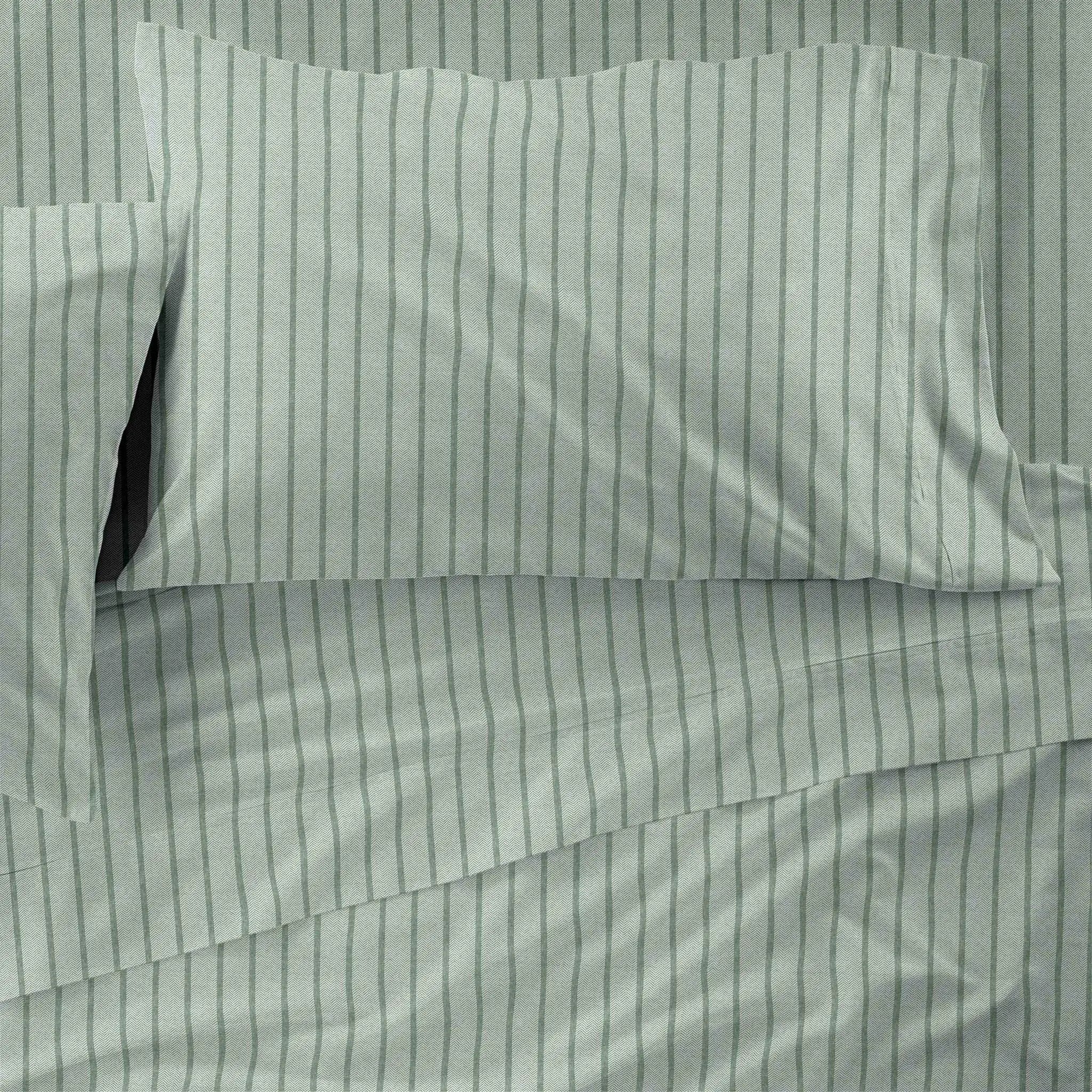 Light sage green bedding set with dark green vertical pinstripes, including a pillowcase and sheet, shown in a close-up flat-lay view.