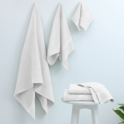 Set of white towels on a white stool against a light blue background