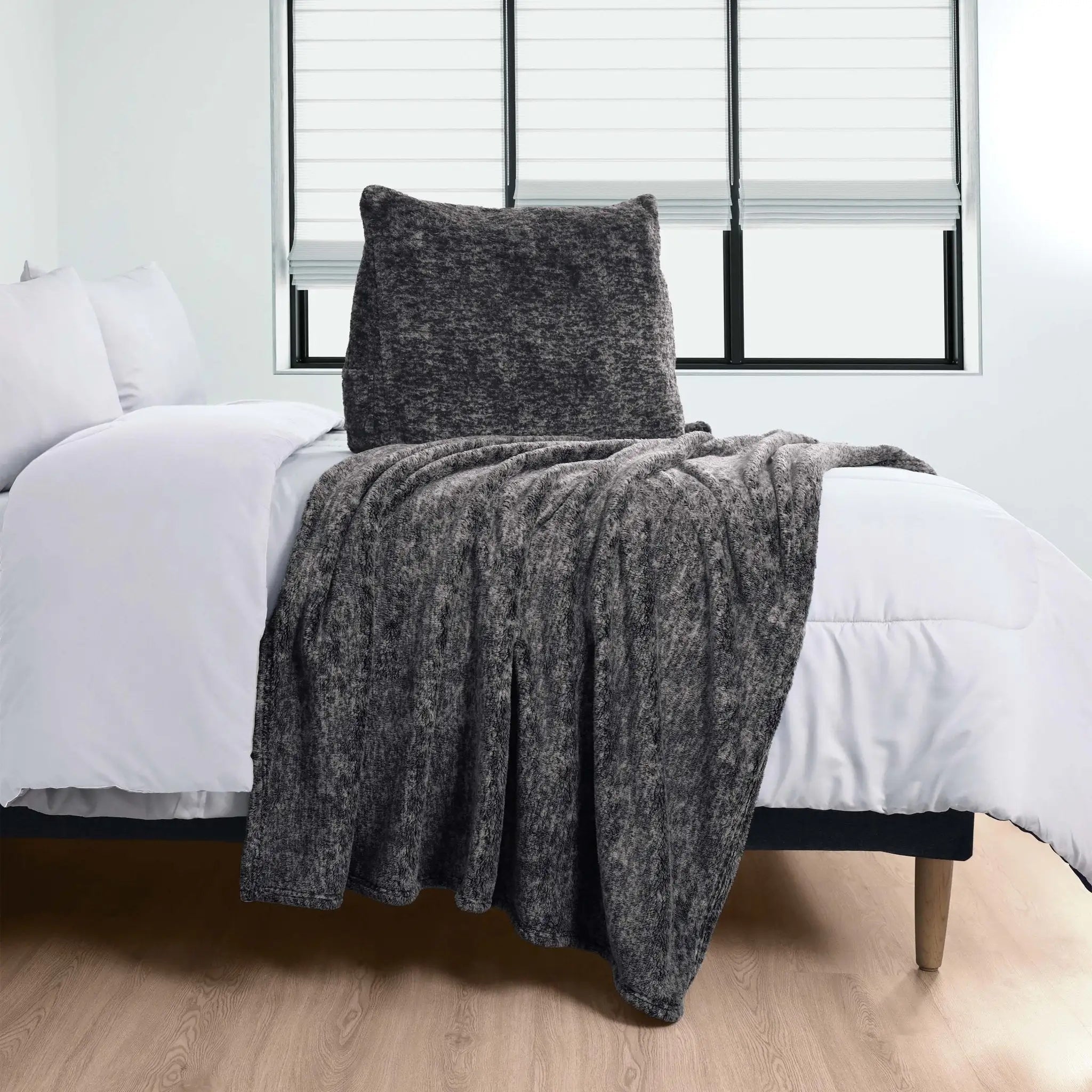 Gray pillow over a bed with white bedding in a room.