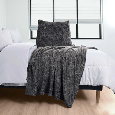 Gray pillow over a bed with white bedding in a room.
