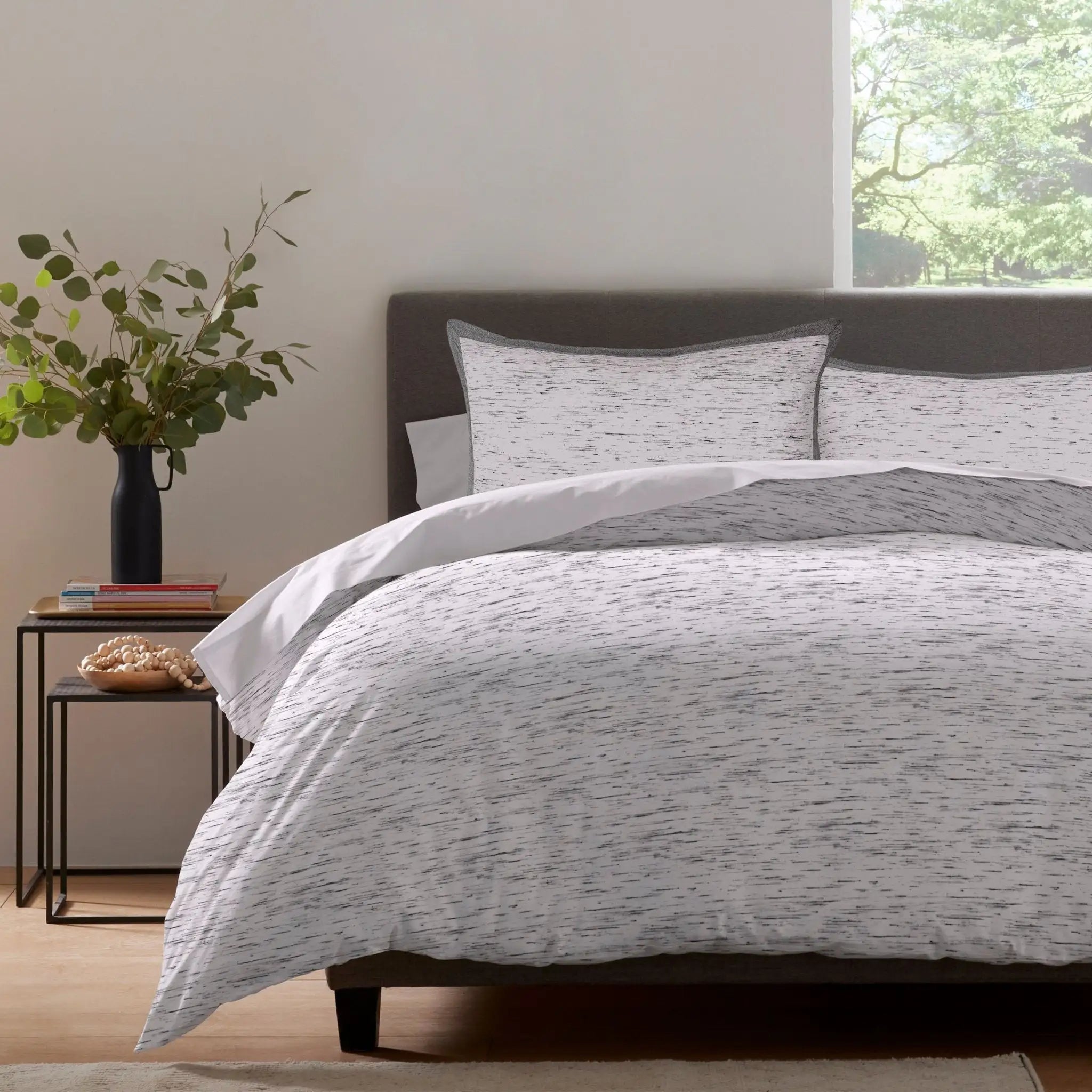 Gray and white patterned comforter set on a bed in a room.