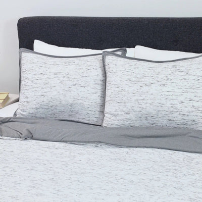 Gray and white comforter set on a bed with a dark gray headboard.