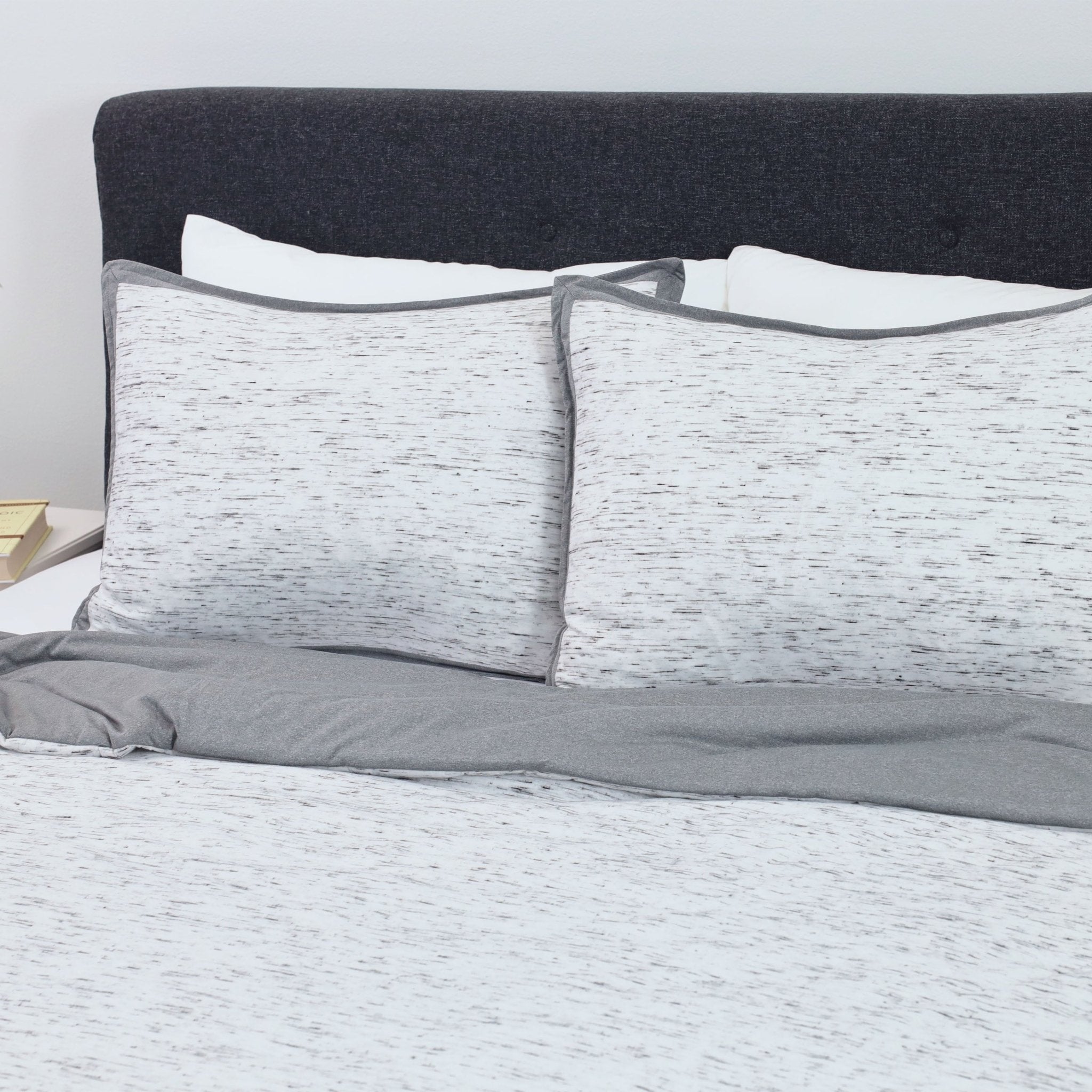 Gray and white comforter set on a bed.