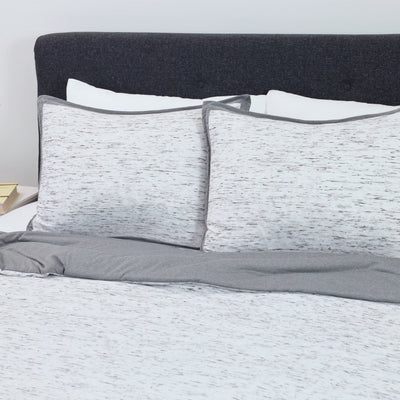 Gray and white comforter set on a bed.