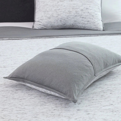 Gray pillow sham on a bed with a white and gray patterned pillow sham in the background.