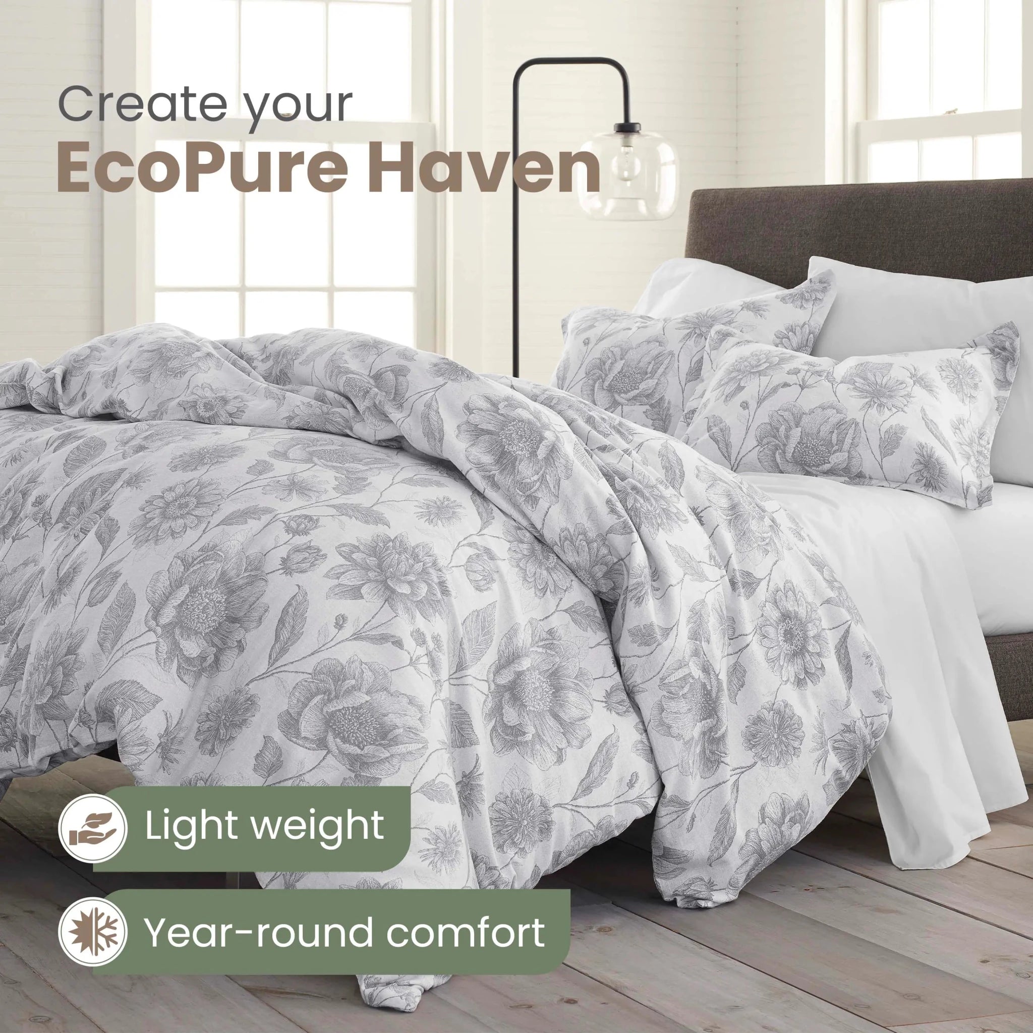 A bed dressed in a light gray and white floral-patterned comforter and matching pillowcases, shown in a bright bedroom setting with text overlays reading 'Create your EcoPure Haven' and 'Light weight Year-round comfort'.