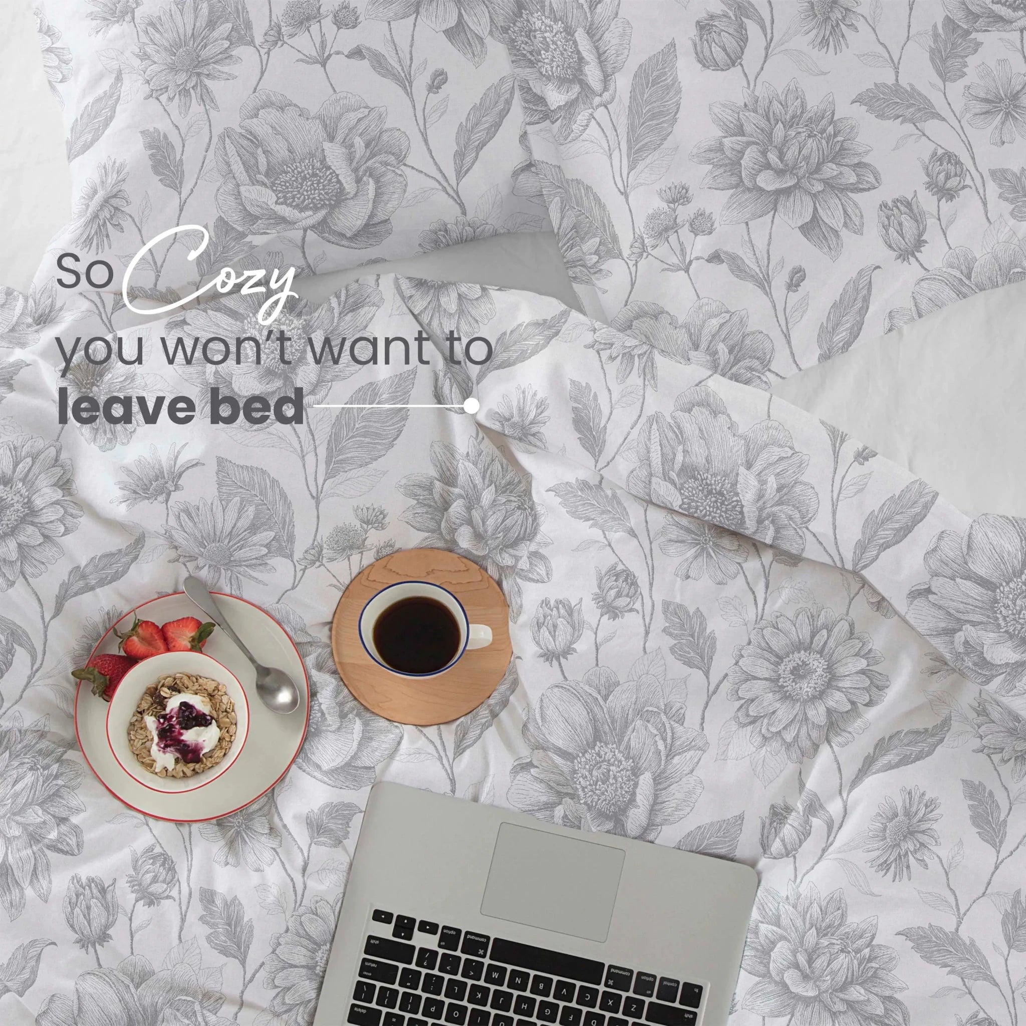 A cozy flat-lay of a white bedding set with a gray floral pattern. Text on the image reads 'So Cozy you won't want to leave bed'.