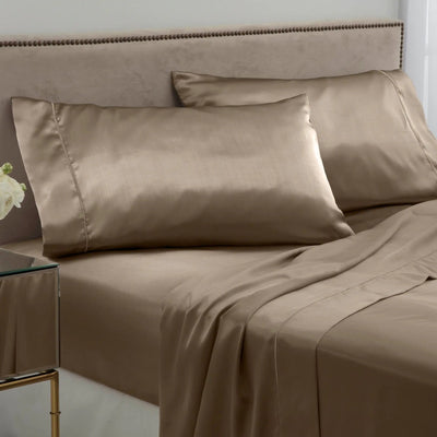 Gold bed sheets and pillows on a neatly made bed with a side table.