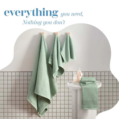 Sage towels hanging on a white towel rack against a tiled bathroom wall.