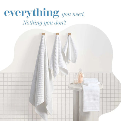 Three white towels hang from wooden hooks on a wall. Decorative text at the top reading 'everything you need, Nothing you don't'.