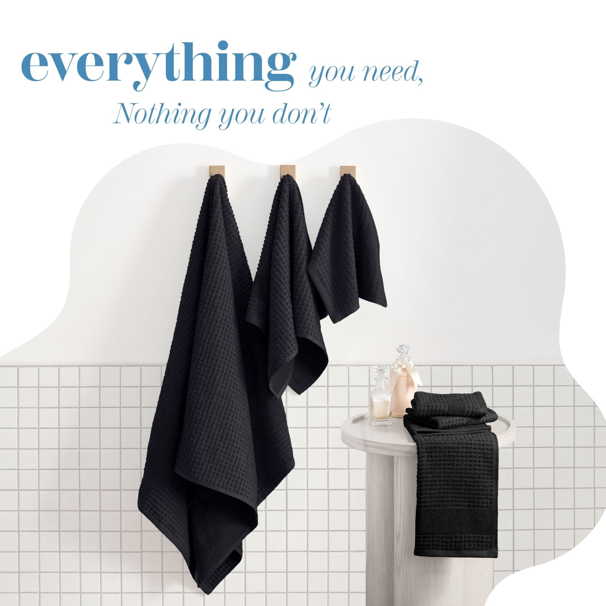 Black towels hanging on a rack with a bathroom setting in the background.