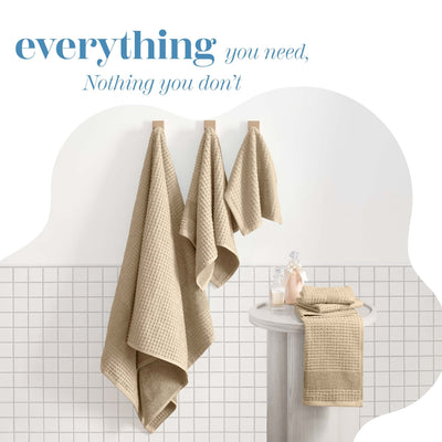 Beige towels hanging on a rack with text 'everything you need, Nothing you don't' on a tiled bathroom wall.