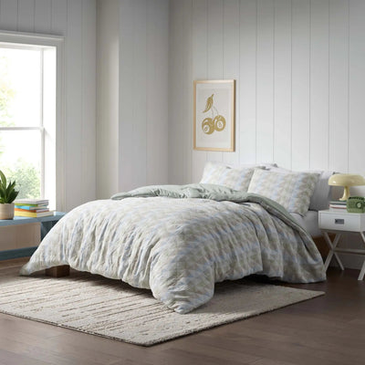 A light blue and white patterned comforter set, styled on a bed in a bright bedroom.
