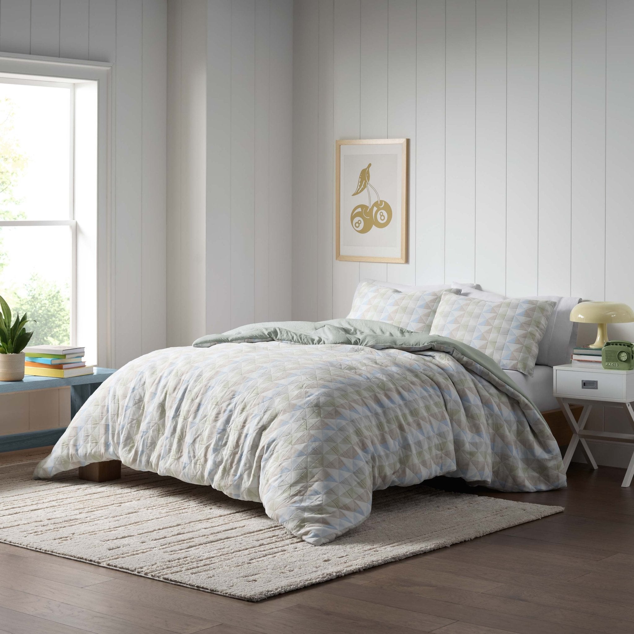 Neatly made bed with light-colored comforter set in a room.