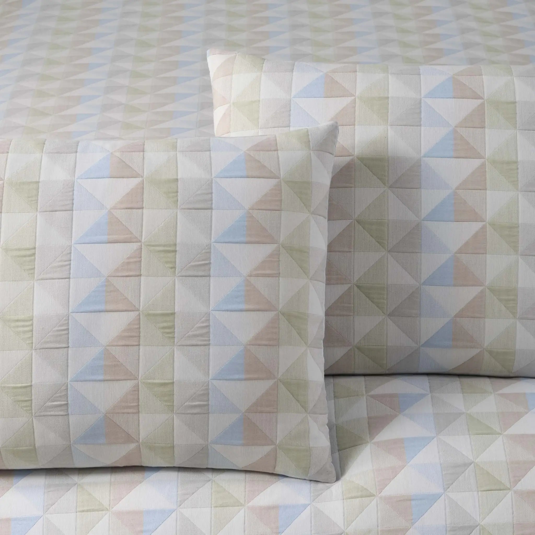 Geometric patterned comforter and pillow sham on a matching fabric background