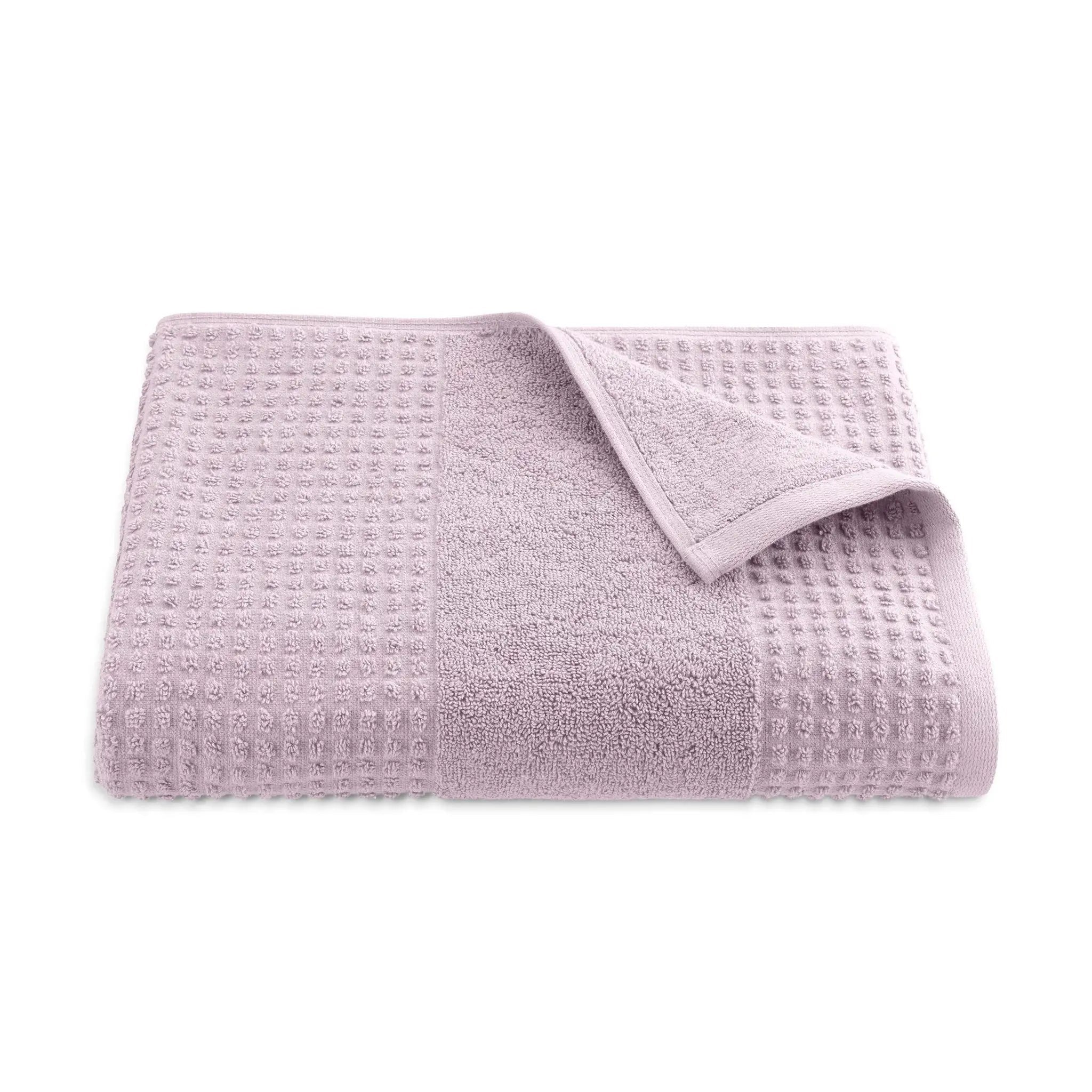 Folded lilac textured bath towel on a white background