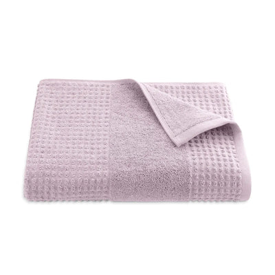Folded lilac textured bath towel on a white background
