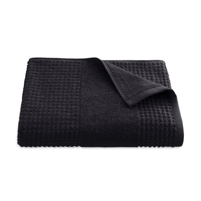 Folded black textured bath towel on a white background