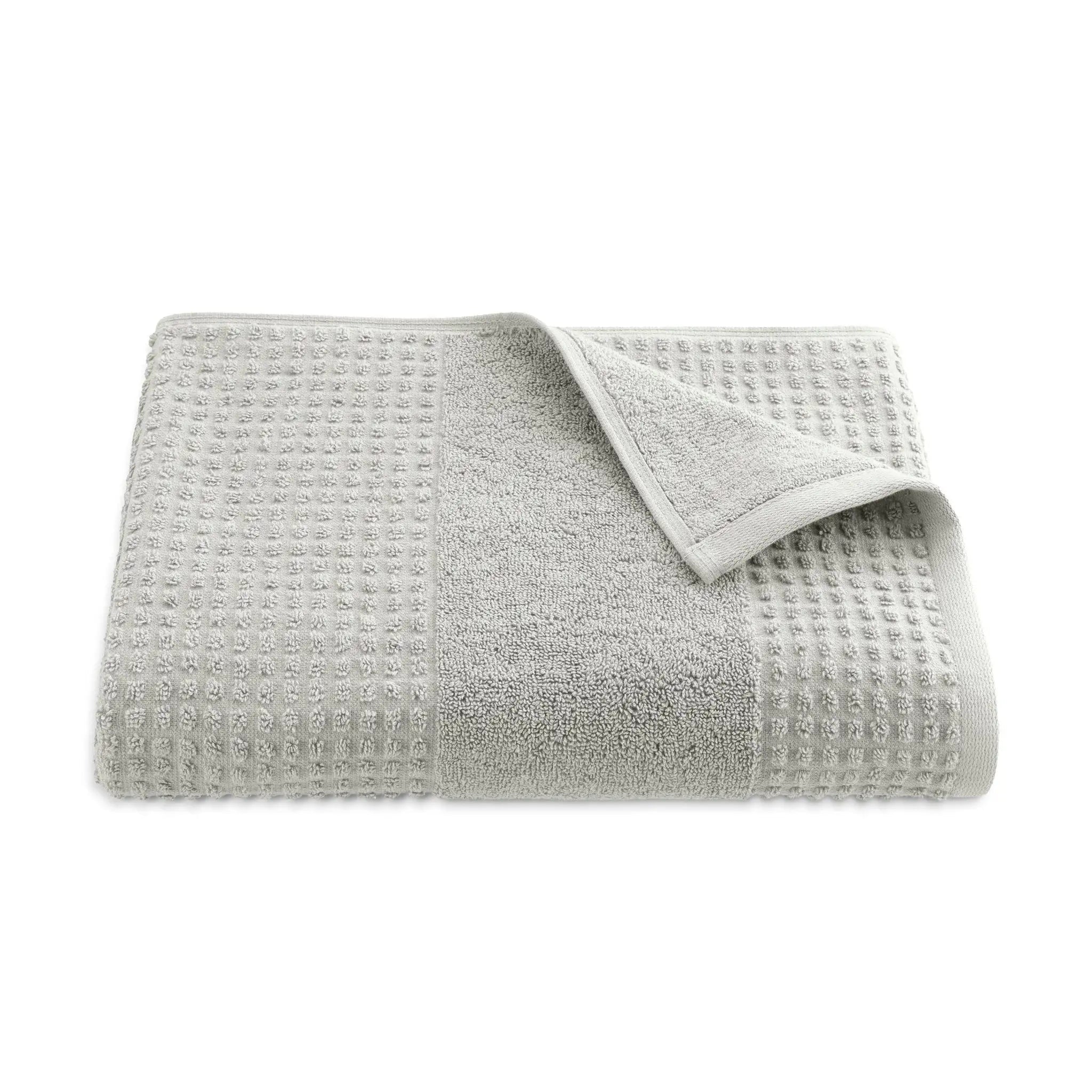Folded grey textured bath towel on a white background