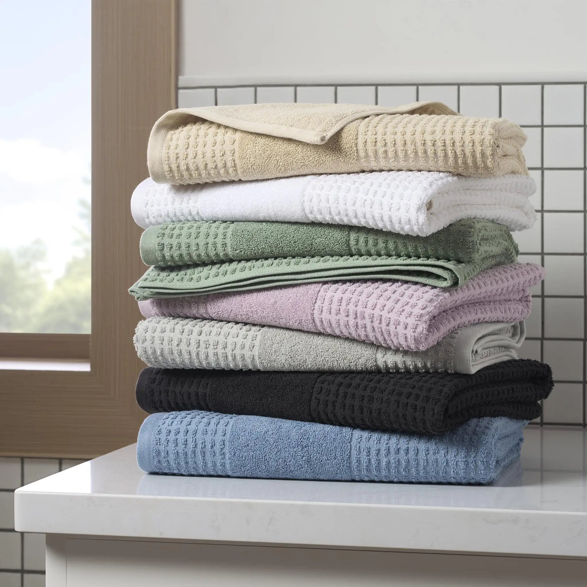 Stack of folded towels in various colors on a kitchen counter.