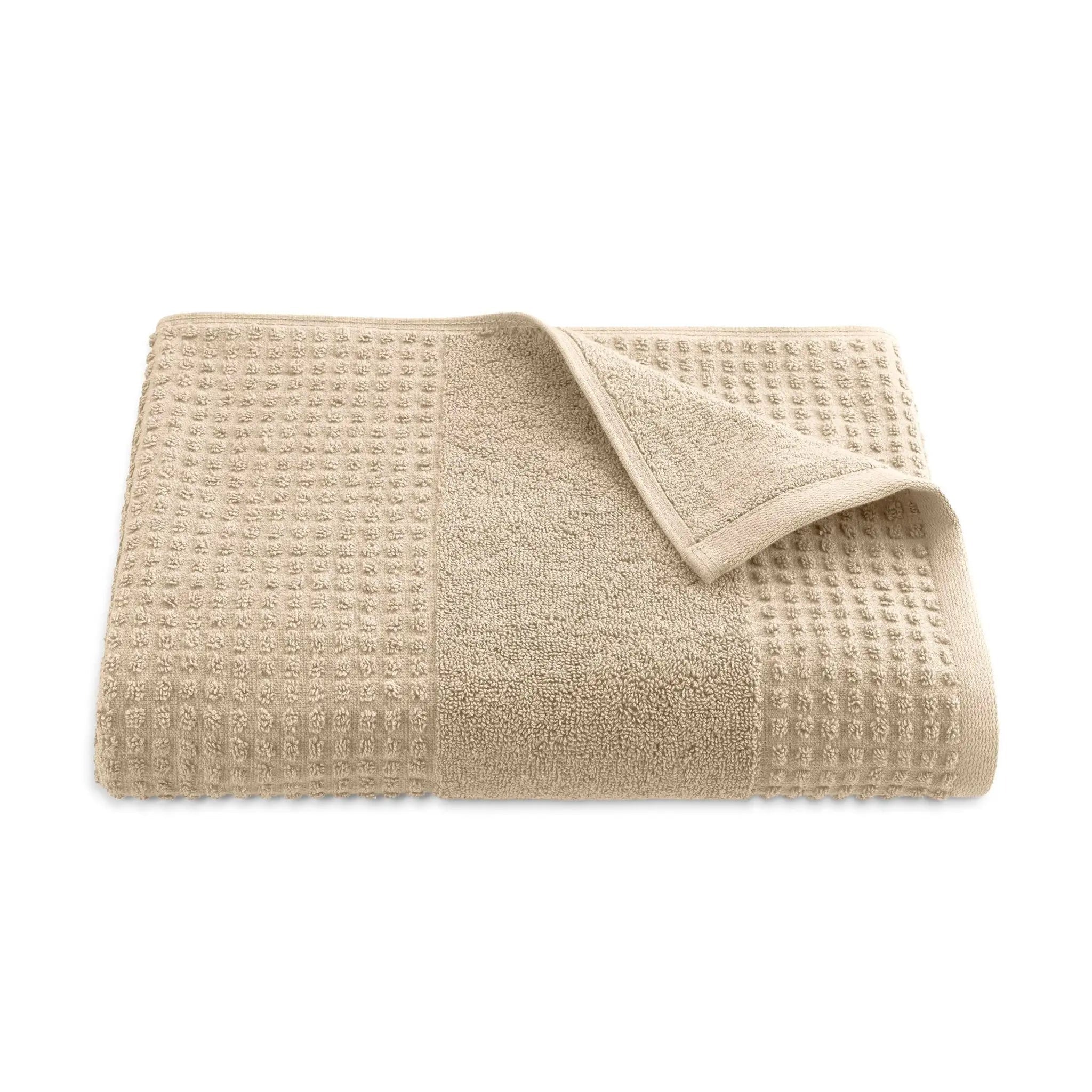Folded sand color textured bath towel on a white background