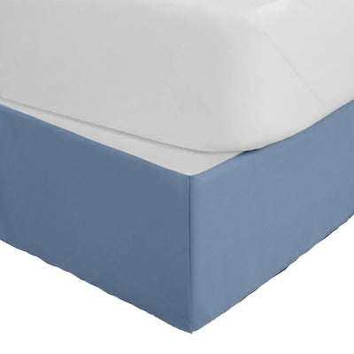 A close-up of a bed frame with a fitted blue bed skirt, shown against a plain white background.