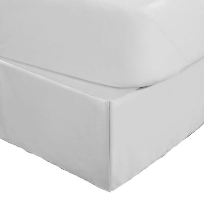 A close-up of a bed frame with a fitted white bed skirt, shown against a plain white background.