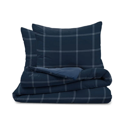 A navy blue bedding set with a white windowpane plaid pattern, including a folded duvet cover and two matching pillow shams, displayed on a clean white background.