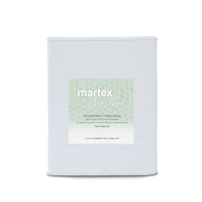 A folded white sheet set package labeled 'martex Restore' with a pale green patterned label, photographed on a clean white background.