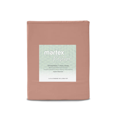 A folded sheet set in a dusty rose pink color, featuring a central white label with the brand name 'martex Restore' and product details, set against a plain white background.