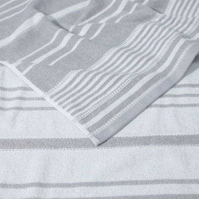A close-up of a striped, grey towel textile and a folded corner showing the fabric texture.