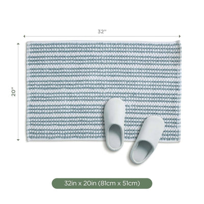 A rectangular mineral bath rug, shown with a pair of white slippers on top. Measurement labels indicate 32 inches by 20 inches, with a green label at the bottom reading 32 in x 20 in (81cm x 51cm).