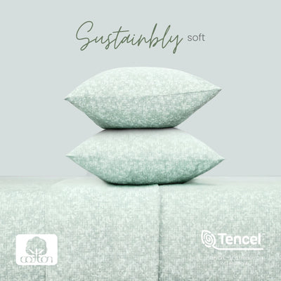 Two stacked square pillows in a pale mint green textured fabric, displayed on a matching upholstered surface against a light gray background. The words 'Sustainably soft' appear above, with cotton and TENCEL logos at the bottom.
