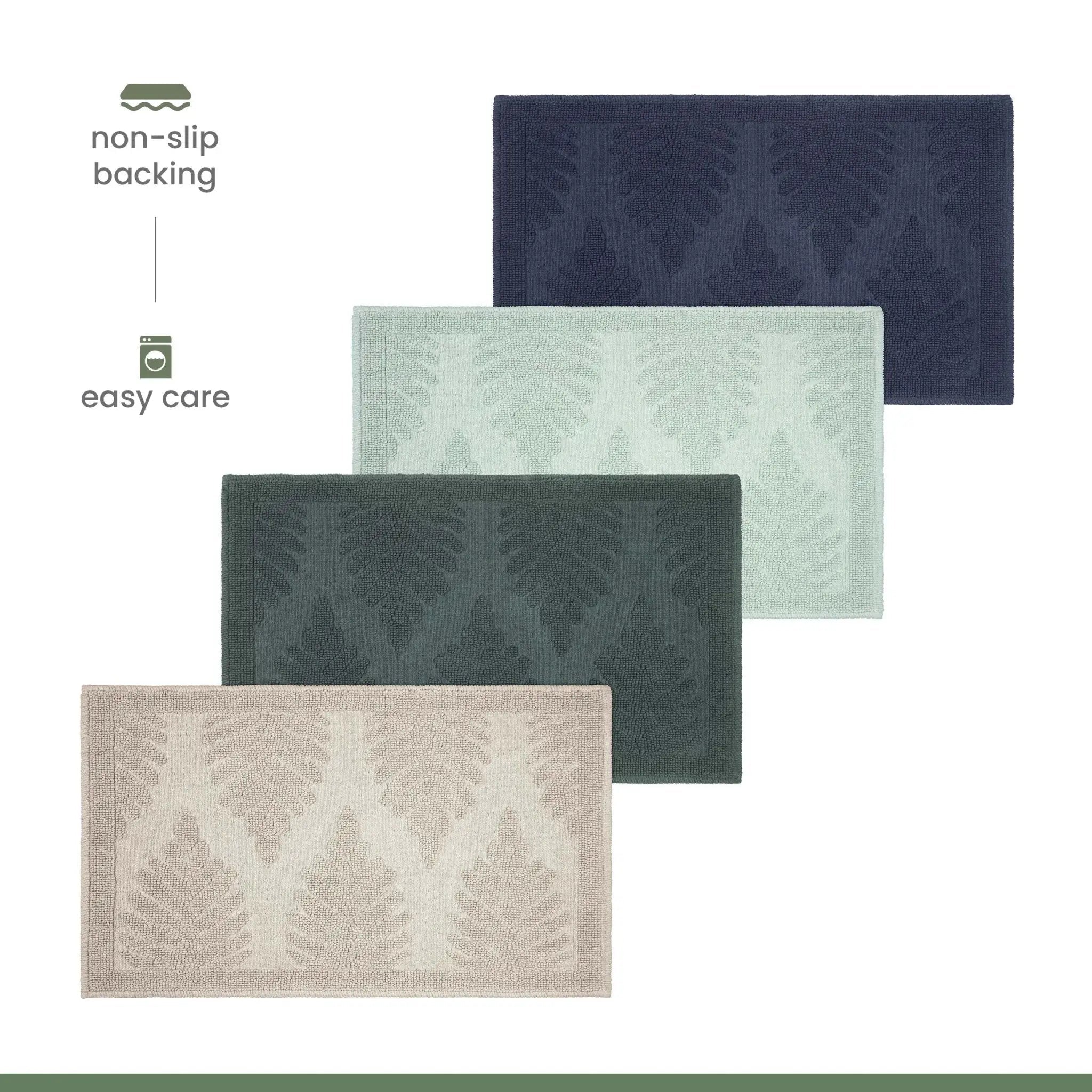 Four rectangular bath mats with a raised fern pattern are shown on a white background, arranged diagonally. The mats come in navy, sage, jade, and sand.