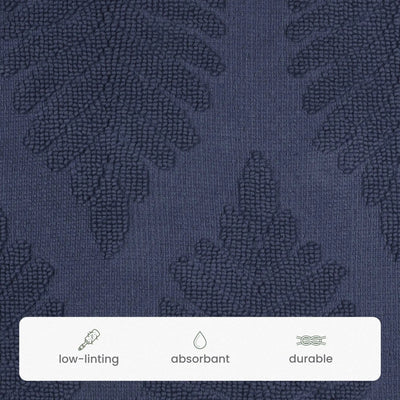 Close-up of a navy textured fabric with a subtle tonal leaf pattern, featuring a white informational strip at the bottom with icons and the words low-linting, absorbant, and durable.