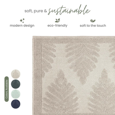 A close-up of a woven bath rug with a textured leaf pattern in sand color, shown on a white background with marketing text and color swatches.