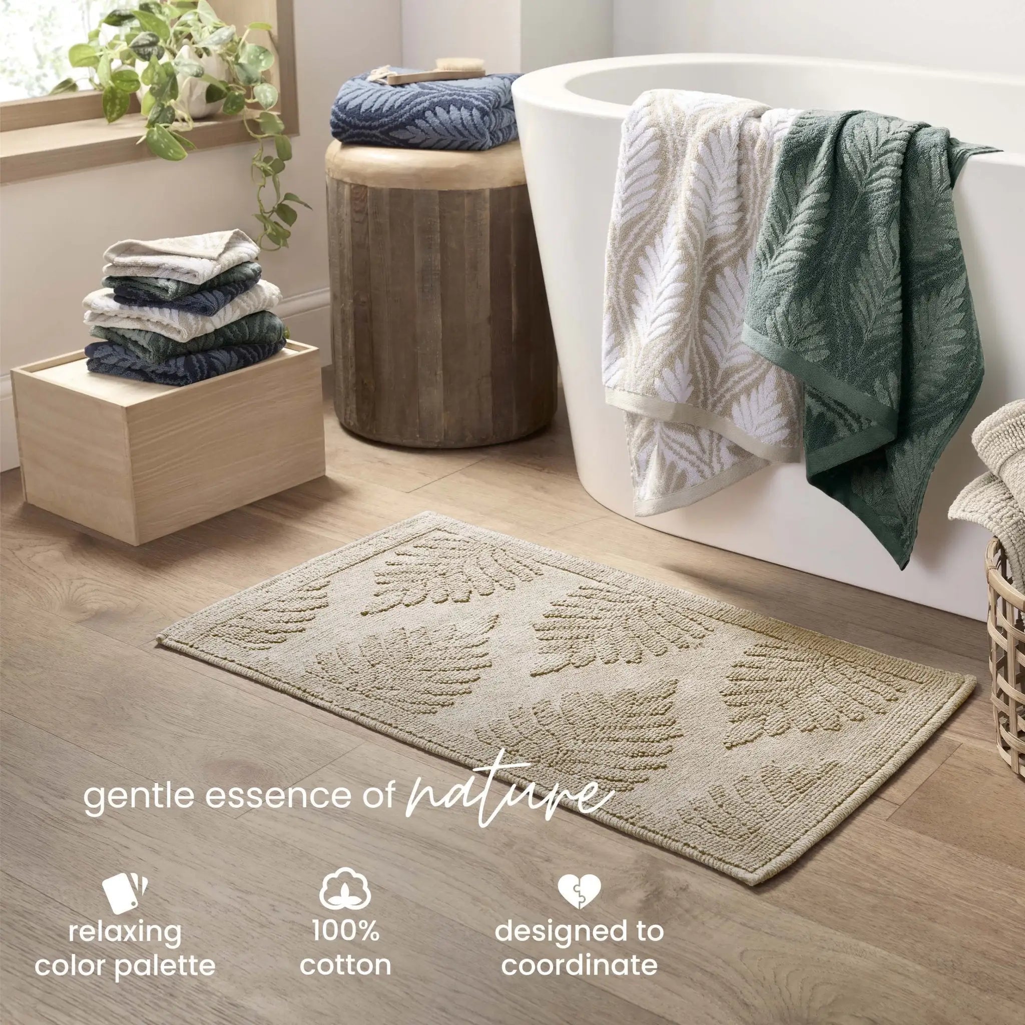A sand color bath mat with a raised leaf pattern is shown in a styled bathroom with folded towels on a wooden stool. Text at the bottom reads 'gentle essence of nature' and includes feature callouts.