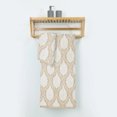 A sand patterned cotton bath towel hangs from a light wood wall-mounted shelf.