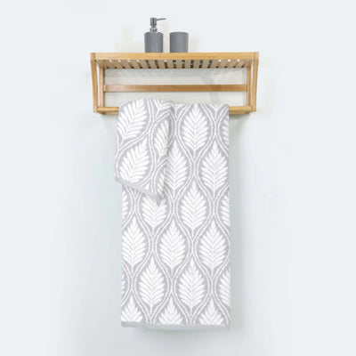 Grey patterned bath towel hanging on a wooden towel rack against a white wall.